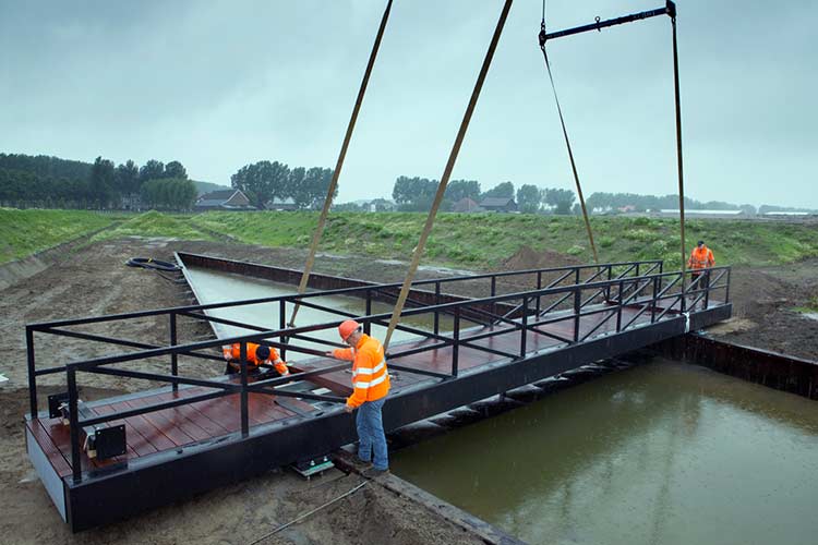 De montage van de brug, boven de golfmaker in de Chladni Vijver in Buitenschot gaat op transport.