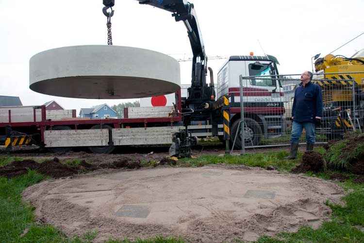 De betonnen sokkel wordt op het zandbed gehesen.